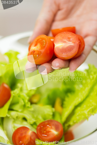 Image of close up of woman cooking vegetable salad at home