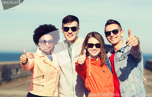 Image of happy teenage friends in shades hugging outdoors