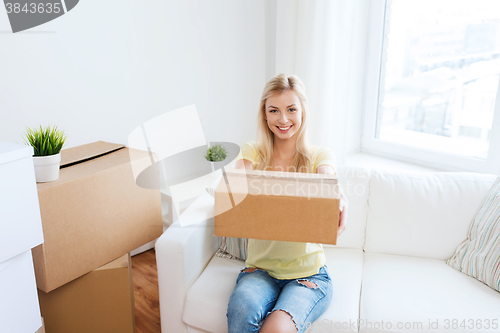 Image of smiling young woman with cardboard box at home