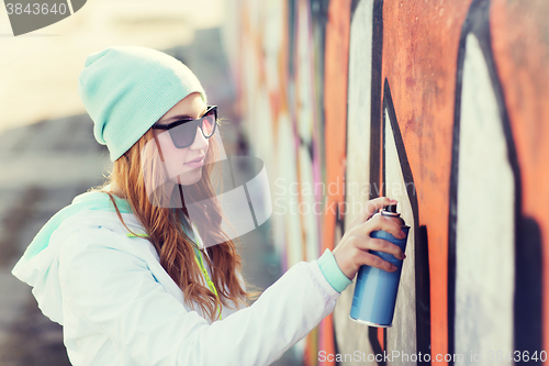 Image of teenage girl drawing graffiti with spray paint