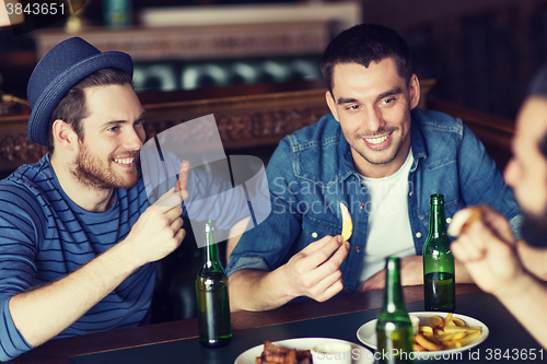 Image of happy male friends drinking beer at bar or pub