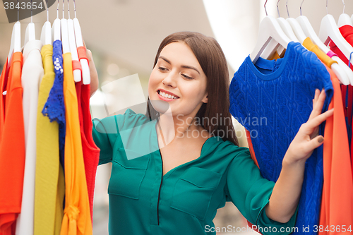 Image of happy woman choosing clothes at home wardrobe