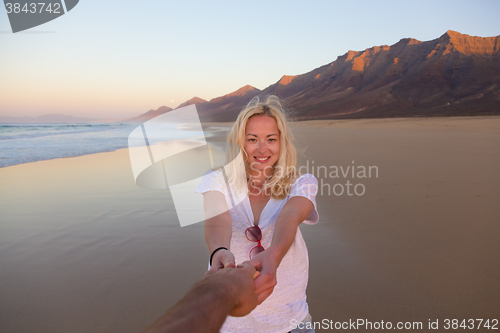 Image of Romantic couple holding hands on beach.