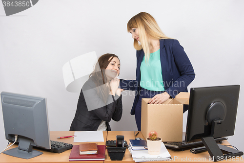 Image of The girl in the office is facing the box with things and says goodbye to a colleague