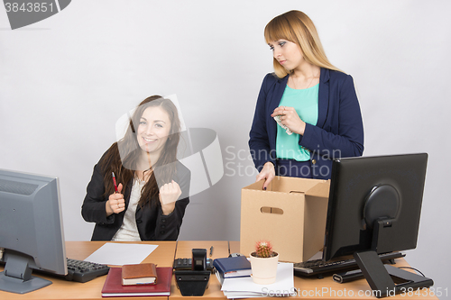 Image of Office worker rejoices that dismissed colleague collects things