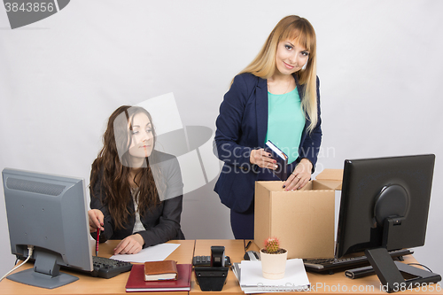 Image of An employee in the office watching colleague who happily collects things