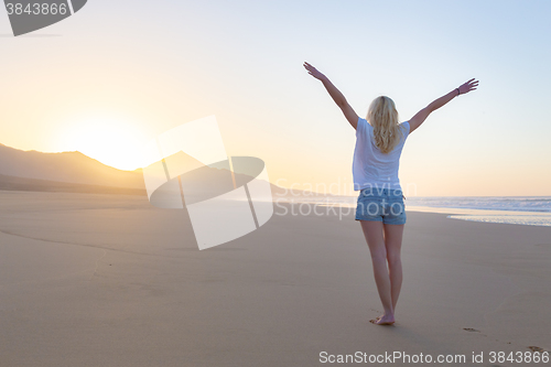Image of Free woman enjoying freedom on beach at sunrise.