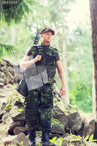 Image of young soldier or hunter with gun in forest