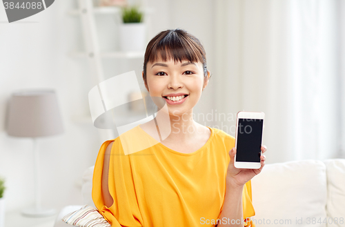 Image of happy asian woman showing smartphone at home