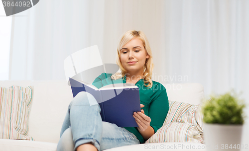 Image of smiling woman reading book at home