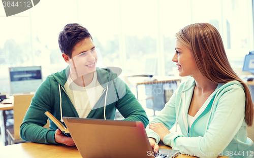 Image of happy students with laptop and books at library