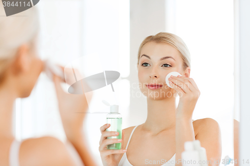 Image of young woman with lotion washing face at bathroom