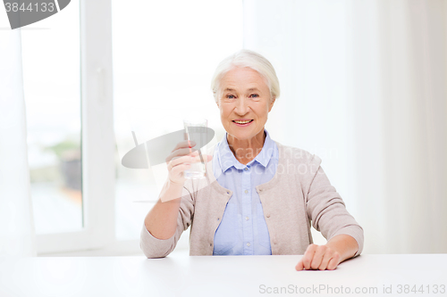 Image of happy senior woman with glass of water at home