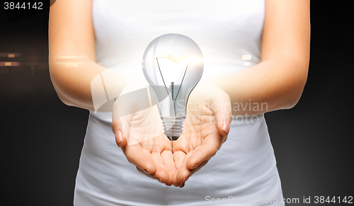 Image of close up of womans cupped hands with light bulb
