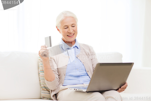 Image of senior woman with laptop and credit card at home