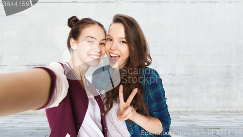 Image of happy friends taking selfie and showing peace