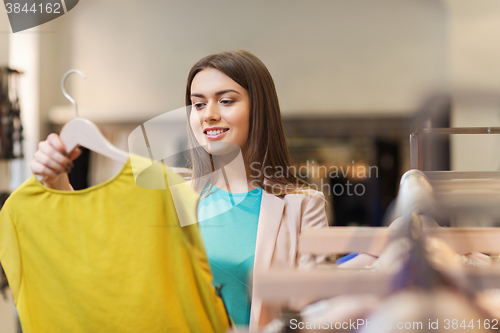 Image of happy young woman choosing clothes in mall