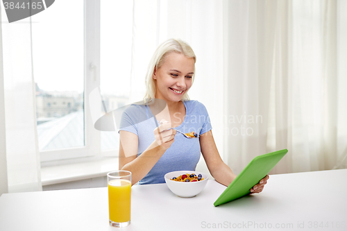 Image of woman with tablet pc eating breakfast at home