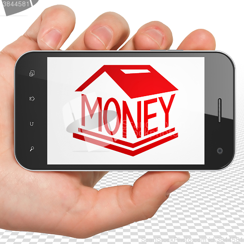 Image of Money concept: Hand Holding Smartphone with Money Box on display