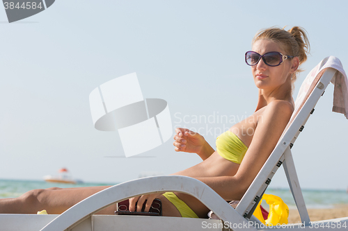 Image of Girl on a deck chair on the beach is going to do a manicure