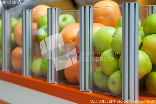 Image of Glass showcase with fresh fruit apples and oranges, focus is positioned on apples