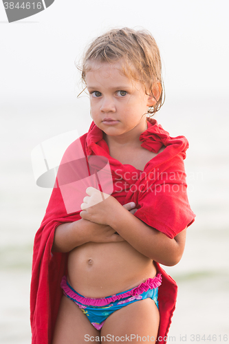 Image of Sad frozen five year old girl wrapped herself in an adult t-shirt