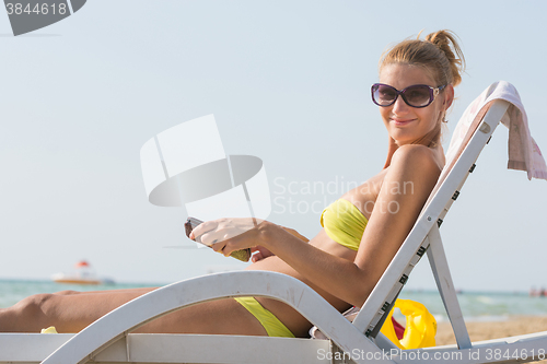 Image of Girl on a deck chair on the beach with a smile look in the frame