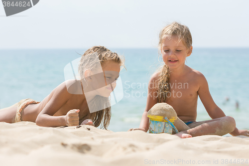 Image of Two little girls are playing with enthusiasm in the sand on the seashore