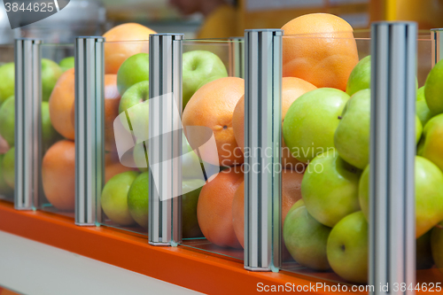 Image of A large glass container showcase fresh fruit apples and oranges, focus is positioned on oranges