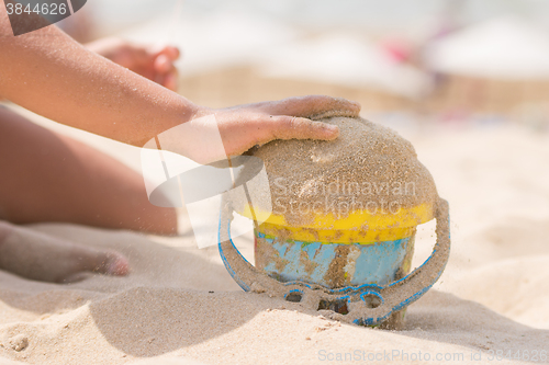 Image of Childrens pen in the bucket pours sand on the beach