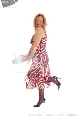 Image of Happy blond woman dancing in dress.