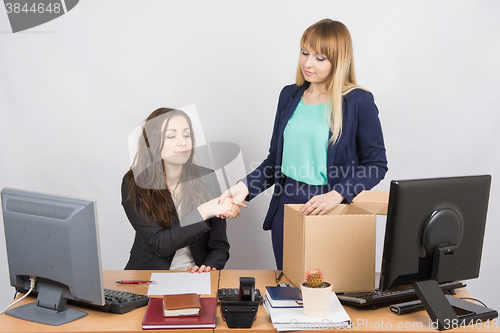 Image of Girl in office standing with a smile in front of the box and shakes hands with a colleague