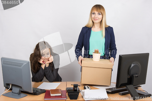 Image of An employee in the office happily keeps things close sad colleague