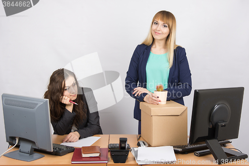 Image of New employee in the office happily keeps things close sad colleague