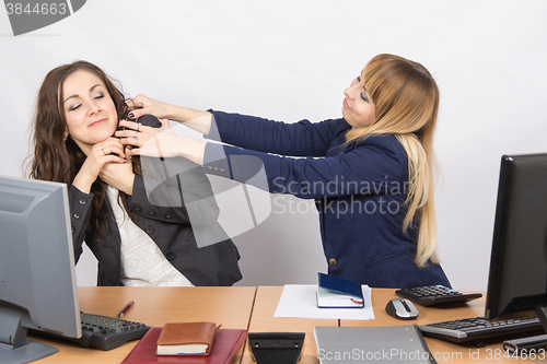 Image of The girl in the office workplace trying to stifle a colleague