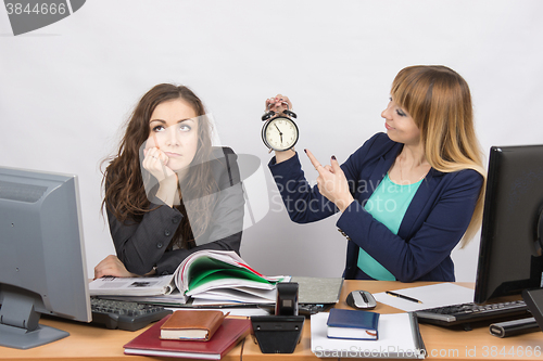 Image of Office employee working at the end of the day, one with a smile, indicating the clock, the other thoughtfully props head