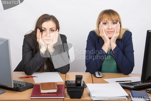 Image of Two tortured worker sitting at desk, resting his head in his hands