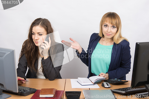 Image of The girl in the office puzzled indicates colleague talking on the phone