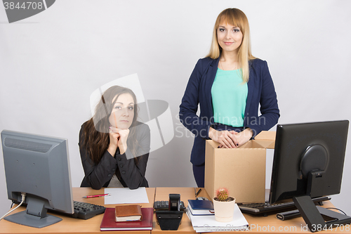 Image of The girl in the office is facing the box with things near the colleague sitting next