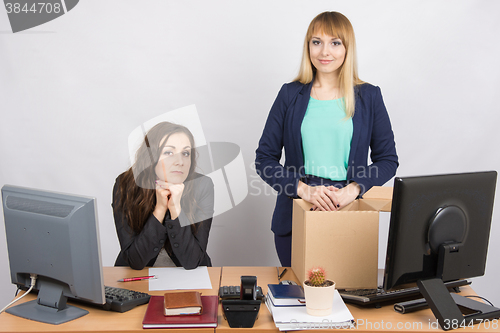 Image of The girl in the office is facing the box with things near the colleague sitting next