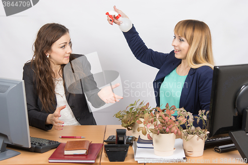 Image of Office employee-grower sprinkles water from pulivizatora on irritated colleague