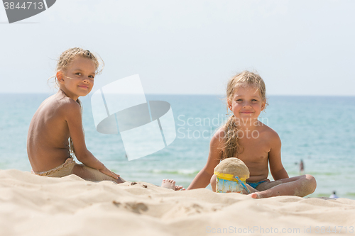 Image of Two girls of four and six years of playing in the sand on the seashore