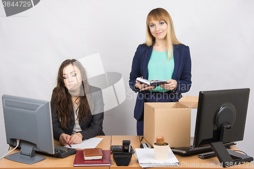 Image of An employee in the office happily puts things out of the box next to a colleague