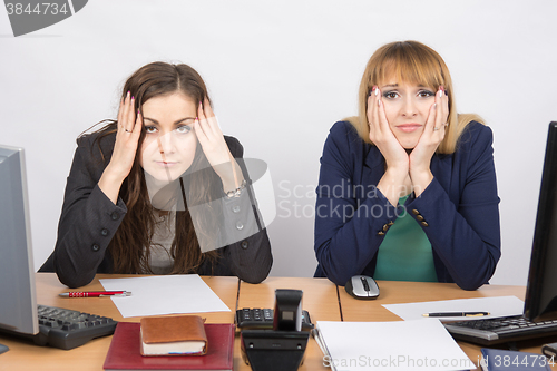 Image of Two office employee sitting with depressed and frightened look