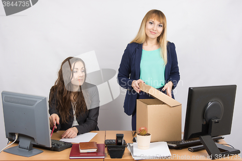 Image of  New employee in the office happily arranges things, next to a colleague