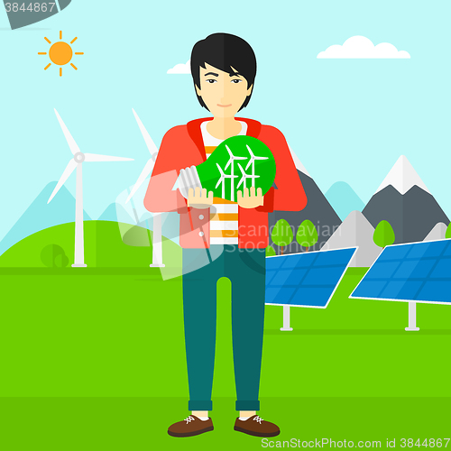 Image of Man holding lightbulb with windmills inside.