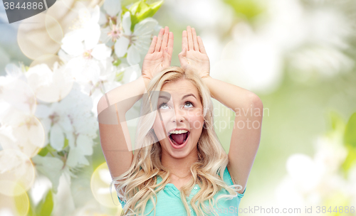 Image of happy smiling young woman making bunny ears