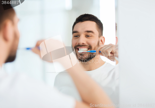 Image of man with toothbrush cleaning teeth at bathroom