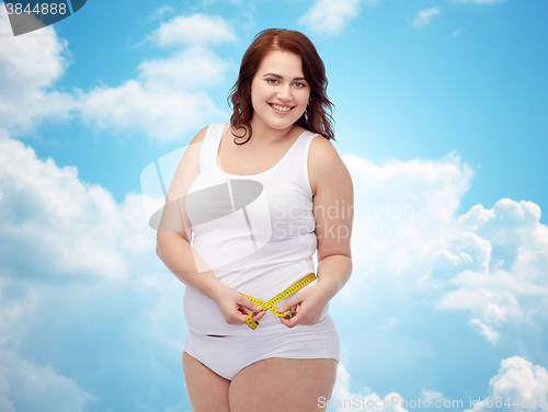 Image of happy young plus size woman with measuring tape