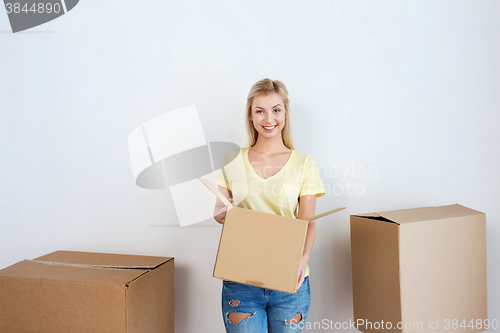 Image of smiling young woman with cardboard box at home